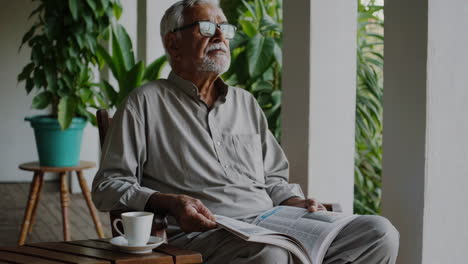 elderly man reading a newspaper on the porch