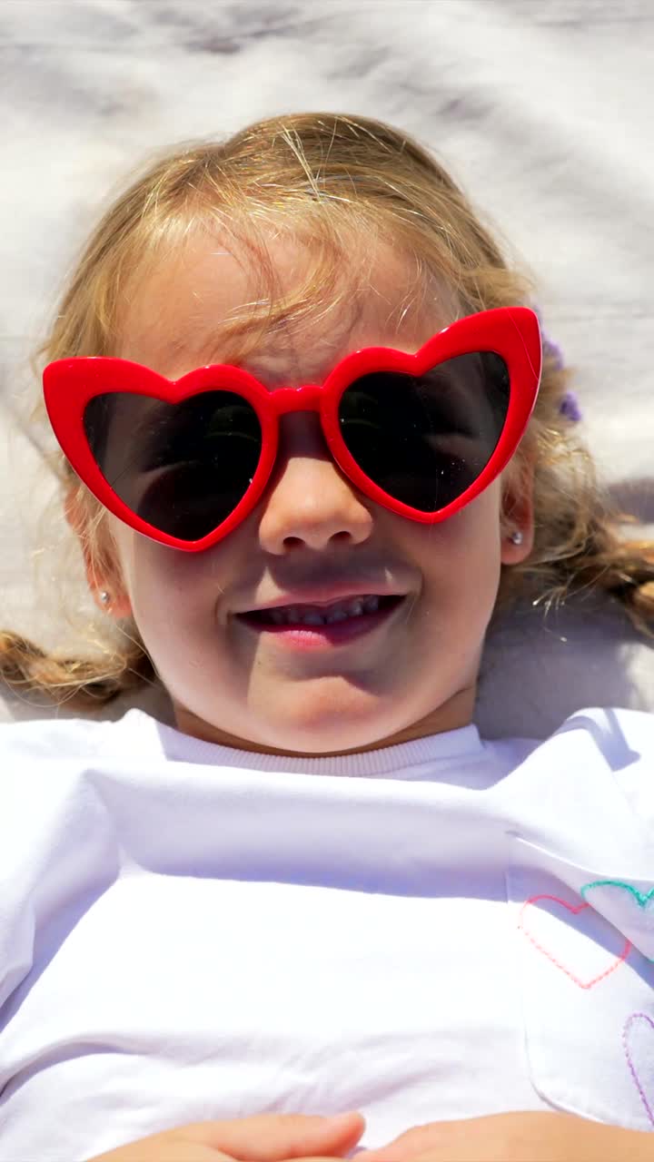 A young girl with red heart sunglasses