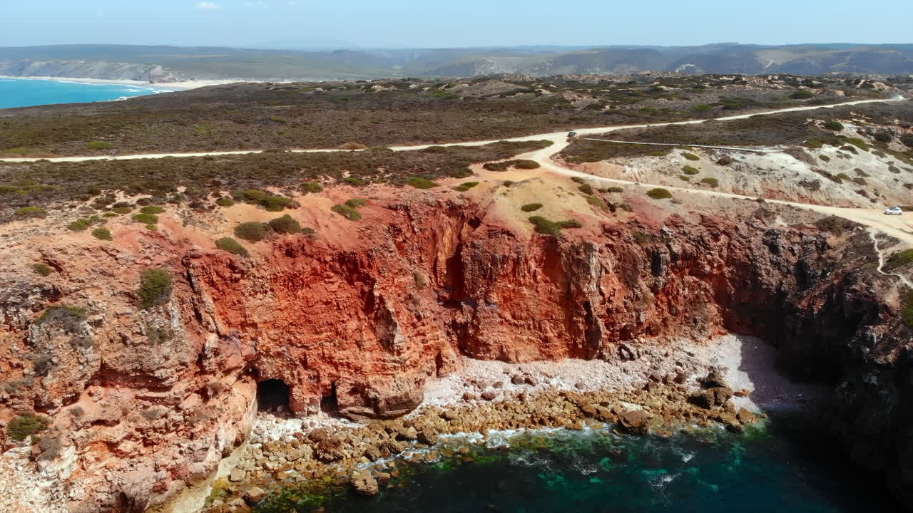 Aerial view of a cliffside landscape with a road near the coast