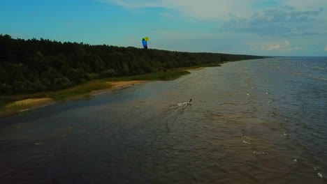 wider view from above of a kite surfer riding the waves