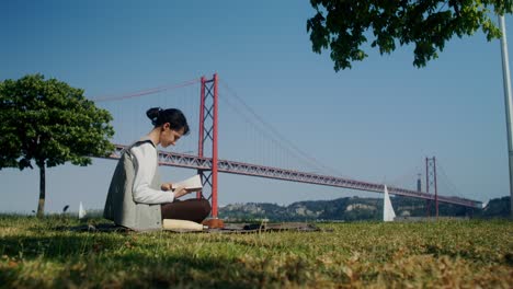 mujer leyendo un libro en un parque junto al puente