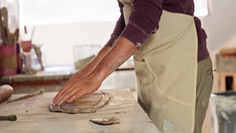 Male-potter-working-on-clay-in-pottery-workshop