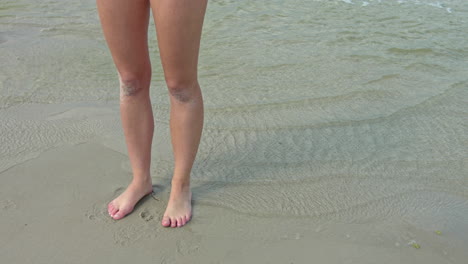 static shot sportive long feminine legs standing at beach sea shore,slow motion