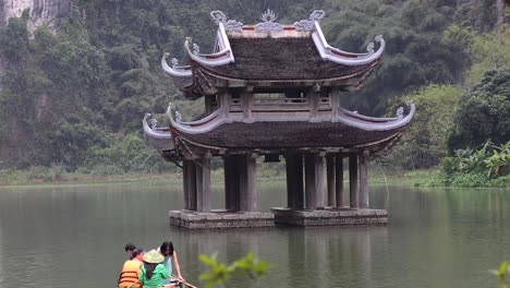 tourists rowing boat near traditional pavilion