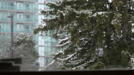 Looking-through-a-window-where-snow-is-falling-in-the-city