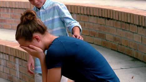 Schoolboy-consoling-her-sad-friend-on-steps-in-campus