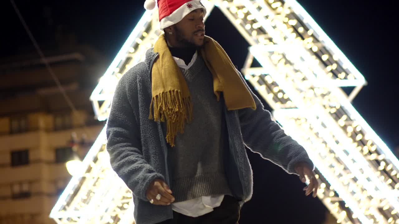 Man in Christmas Hat and Scarf near Christmas Lights