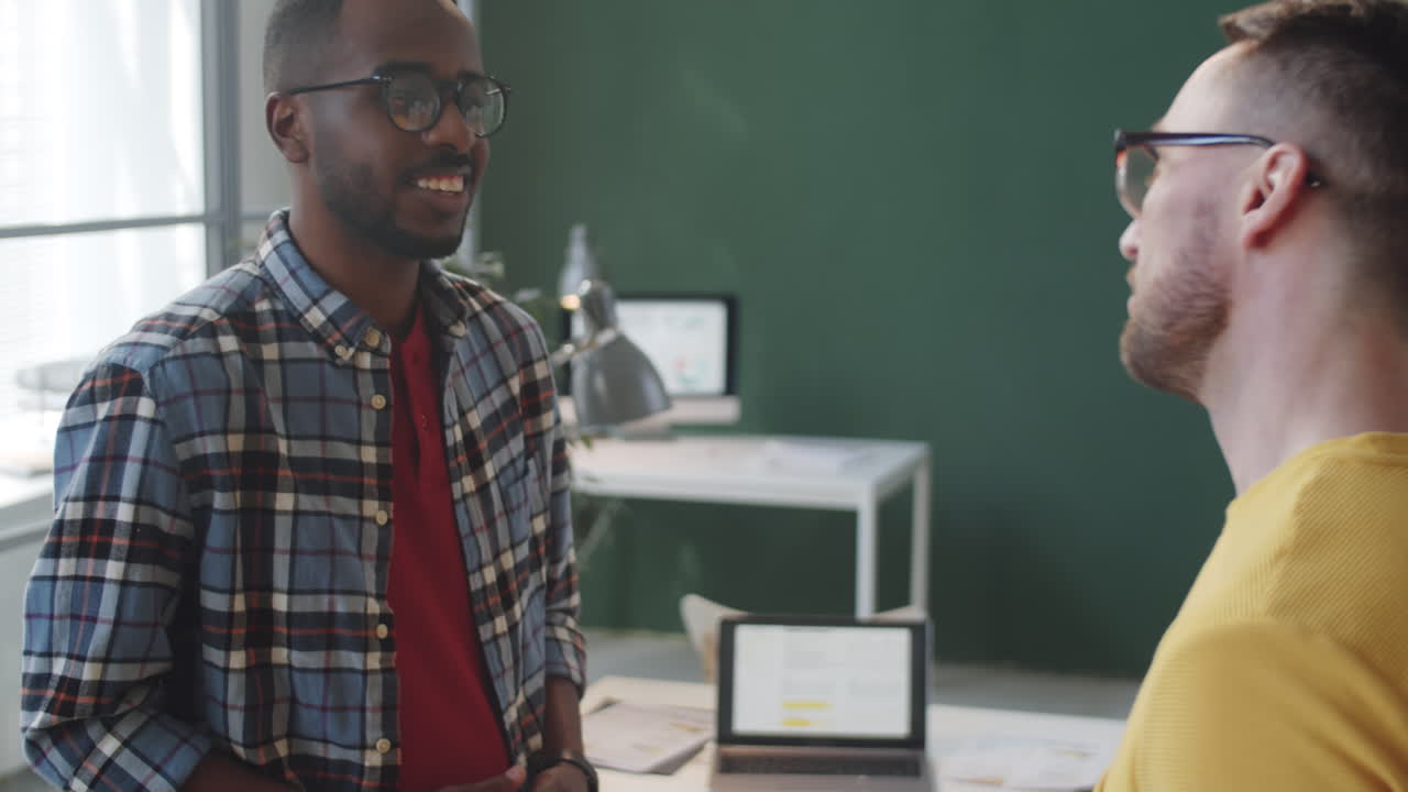 Young Multiethnic Coworkers Shaking Hands and Chatting in Office