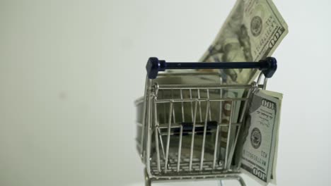 shopping cart loaded with usd 100 bills spinning on white background