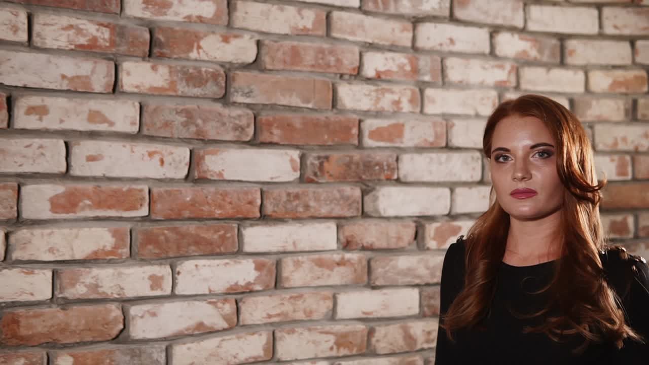mujer frente a una pared de ladrillo