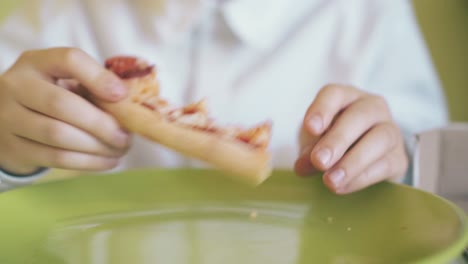 Fröhlicher-Junge-Isst-Pizza-über-Grünem-Teller-Am-Tisch,-Nahaufnahme