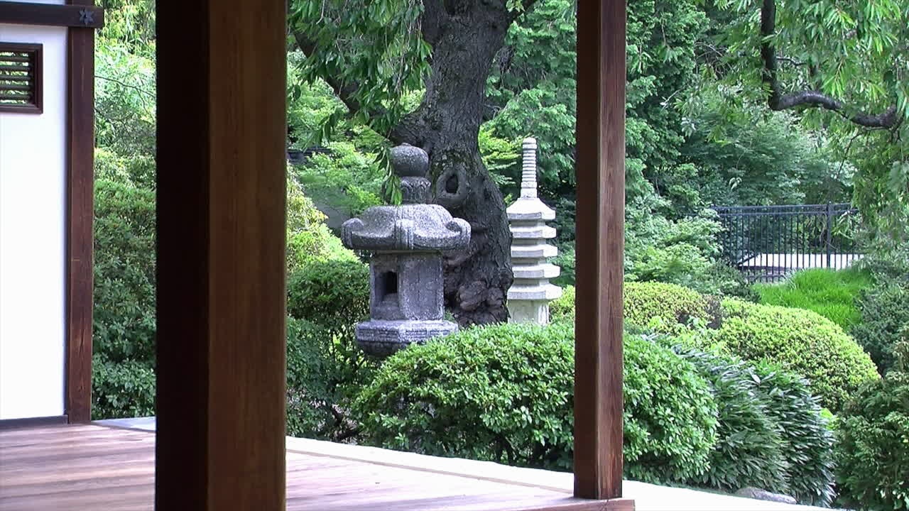 una linterna de piedra y una pagoda en un jardín japonés visto desde un engawa