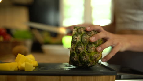 close up of female hands cutting a slice of pineapple