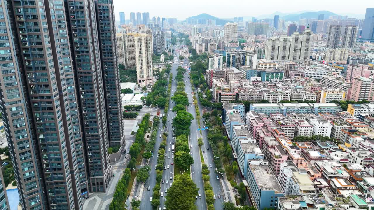 Aerial view of Shenzhen, China, showcasing bustling traffic along a tree-lined avenue amidst a mix of high-rise buildings and urban architecture, symbolizing modern city life.