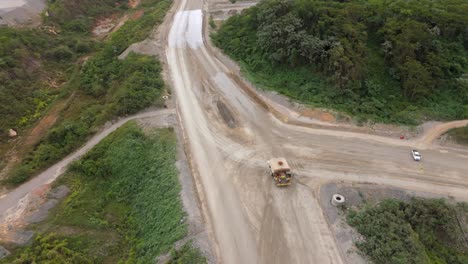 water truck spraying dirt road for dust suppression at mine site, cotui, industrial operations, environmental control, dominican republic. aerial drone top-down view