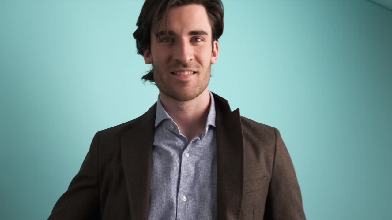Smiling man in jacket looking at camera in blue studio