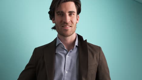 smiling man in jacket looking at camera in blue studio