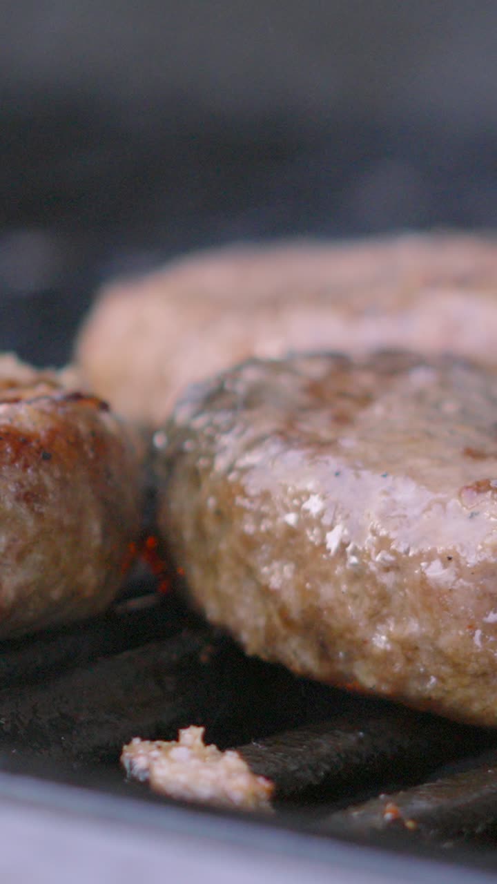 Vertical Video Close Up of Juicy Beef Burgers on BBQ with Flames Cooking Hamburgers from Below. Summer Food.