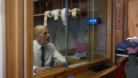 Woman weighing a parcel package in front of a cashier in a post office at the counter window