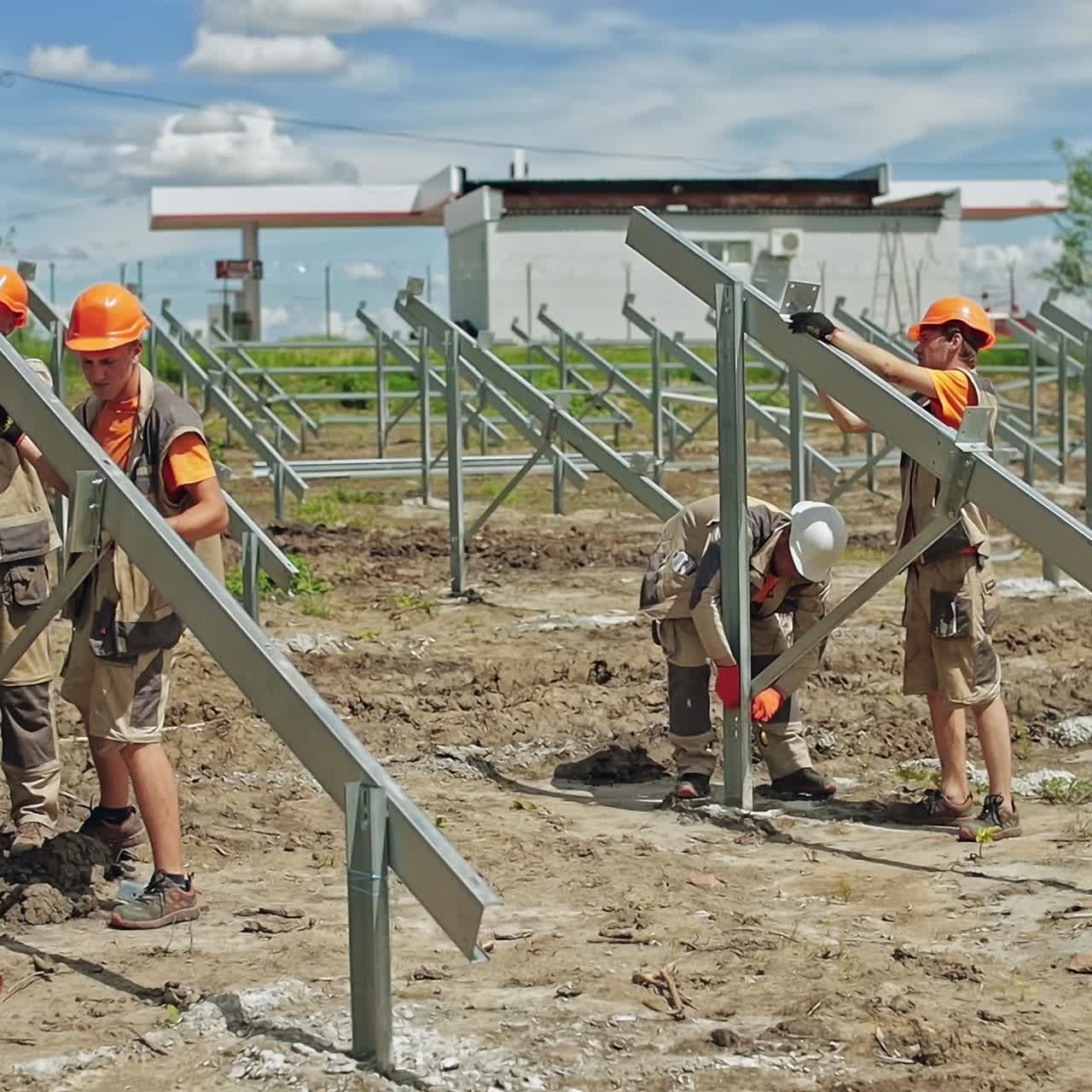 Metal construction for solar panels. Workers in protective helmets build new solar farm on the field in summer.
