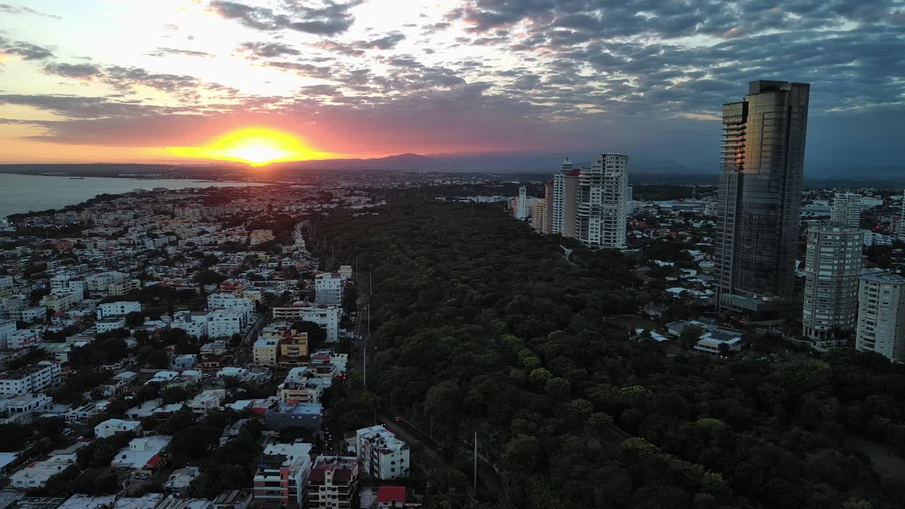 Santo Domingo cityscape at sunset, Mirador Sur park, modern skyscrapers, and Caribbean Sea, Dominican Republic. Aerial drone panoramic view