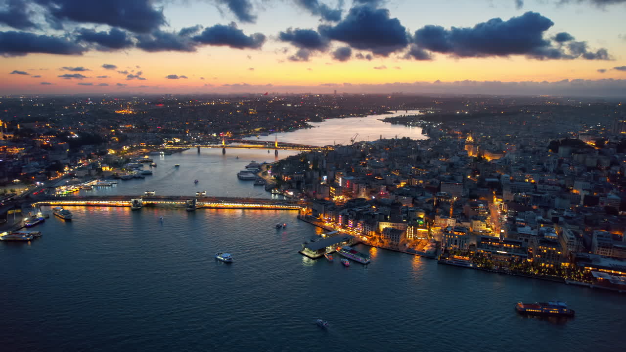 Aerial drone view of Istanbul at sunset, Turkey. Multiple residential buildings, mosques, Galata and Metro bridges over the Golden Horn waterway with multiple floating ships, nightlights