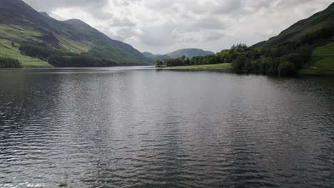 Low-drone-shot-flying-forwards-over-Crummock-Water-on-a-sunny-day,-Lake-District,-Cumbria,-UK