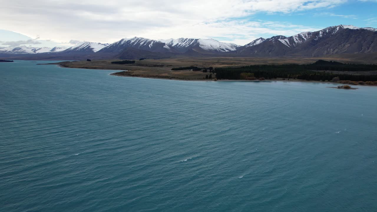 Snowy Mountain Range With Lake Tekapo In The Foreground In South Island, New Zealand. - aerial shot
