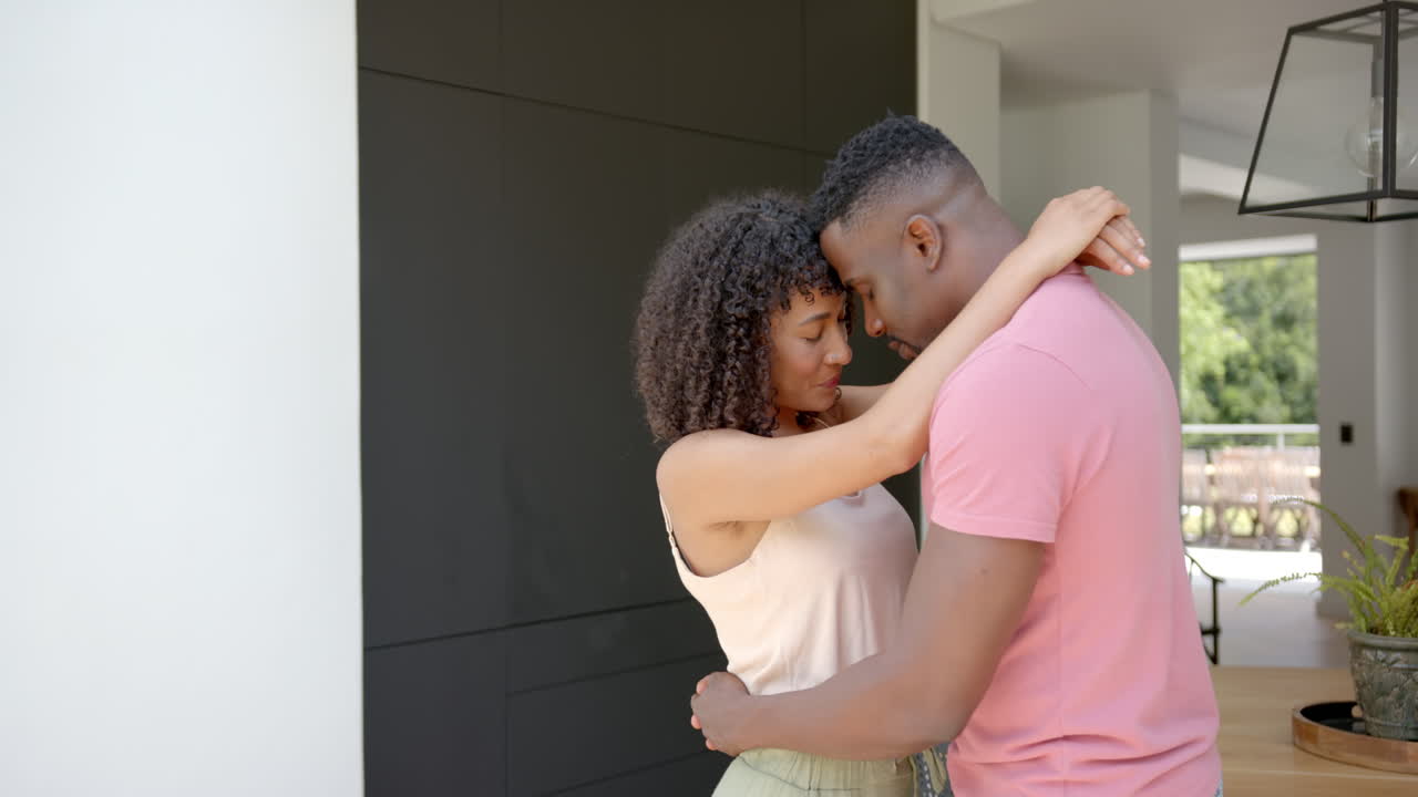 Embracing and smiling, couple enjoying intimate moment together at home
