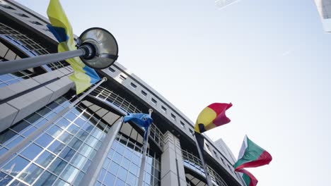 Banderas-De-Varios-Países-Europeos-Y-Ucrania-Ondeando-Frente-Al-Edificio-Del-Parlamento,-Bruselas---Cámara-Lenta