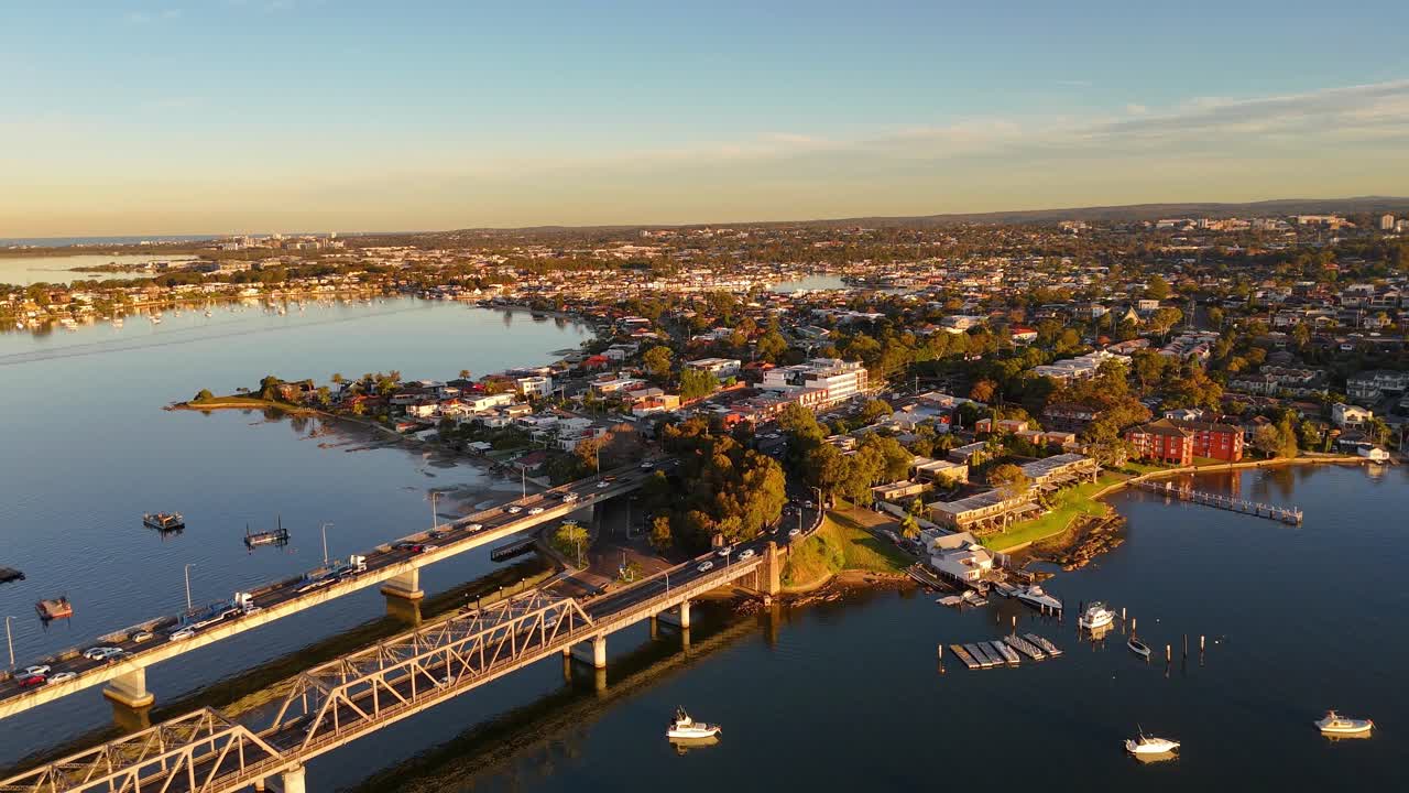 Aerial of Sylvania bridge and urban area with road traffic and boats in evening light, establishing overview, Sydney NSW Australia