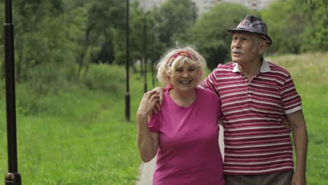 Senior-caucasian-couple-walking-in-park-embracing.-Elderly-man-walks-with-woman.-Husband,-wife