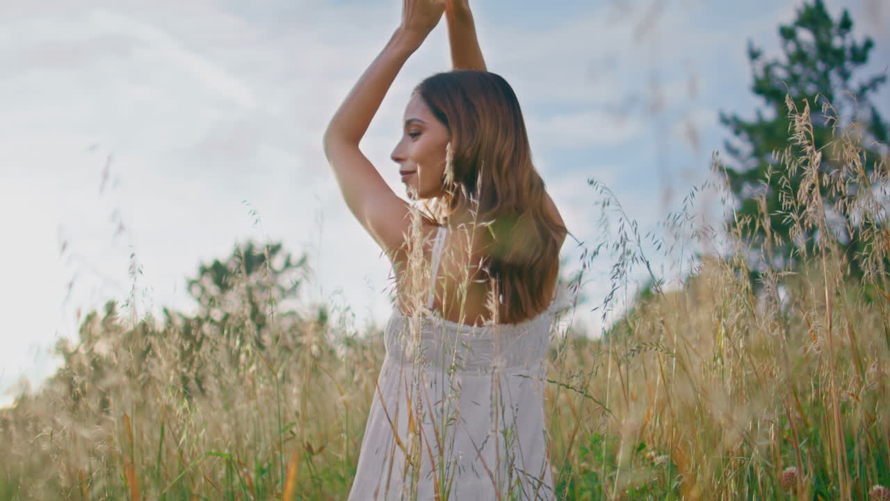 Rural woman raising arms enjoying morning back view. Gentle lady feeling freedom
