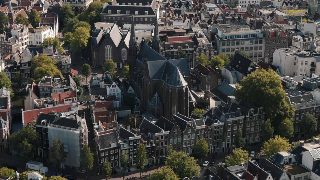 Aerial orbit of Amsterdam church with city buildings and canal visible below