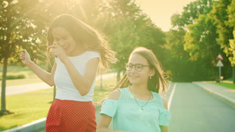 Girl-and-woman-dancing-in-park.-Mother-and-daughter-gesturing-with-hands