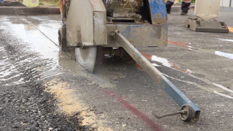 worker is using power tool to cut asphalt to correct measure