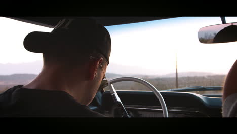 young man in the driving seat of old car, back view close up
