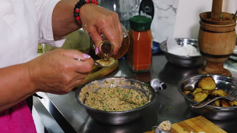 pouring vinegar in tablespoon to add to spread in bowl on kitchen desk