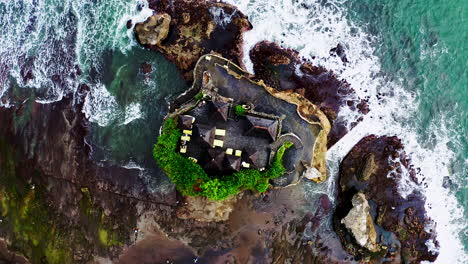 ancient hindu pilgrim tanah lot temple on rocks above sea waves, bali