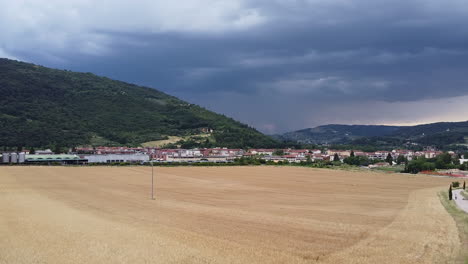 Los-Campos-Marrones-De-Plantas-En-La-Ciudad-Bajo-El-Fondo-Del-Cielo-Tormentoso-Con-Altas-Montañas---Tiro-Ancho