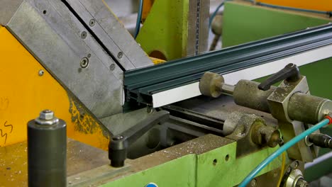 las manos de los trabajadores cortan el perfil de aluminio con sierra circular en la máquina en la fábrica.