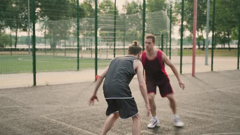 Ein-Geschickter-Basketballspieler,-Der-Den-Ball-Zwischen-Den-Beinen-Gegen-Seinen-Gegnerischen-Verteidiger-Dribbelt-Und-Den-Ball-In-Den-Basketballkorb-Im-Freien-Wirft-2