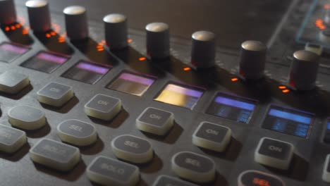 a close-up panning shot of a music mixer board with colorful buttons and knobs