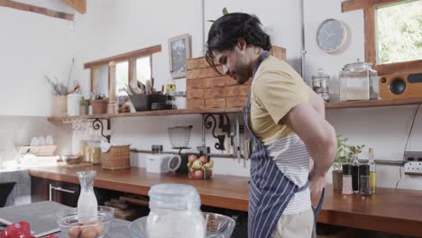 caucasian man wearing apron in kitchen, slow motion