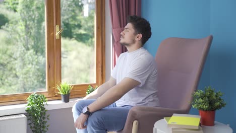 the man in front of the window, taking a deep breath and closing his eyes.