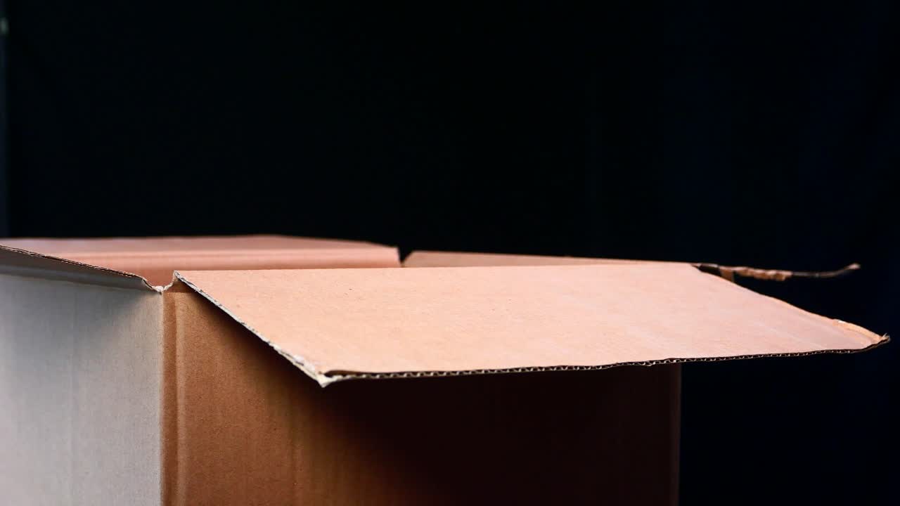 빨간색 물체가 열린 카드보드 상자에 떨어집니다.