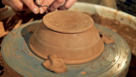a potter carves the foot of a new bowl.