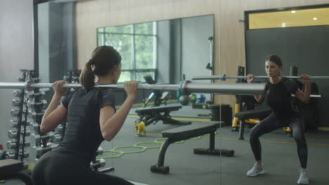 mujer realizando sentadillas con barra en un gimnasio