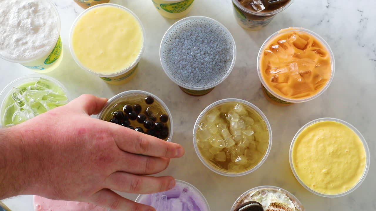 평평한 배열에서 맨 위에 보바가 있는 아이스 티를 집어드는 남성 손