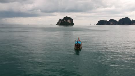 Imágenes-De-Drones-De-Un-Bote-De-Cola-Larga-Navegando-Alrededor-De-Las-Islas-De-Tailandia-Con-Las-Formaciones-Rocosas-De-Piedra-Caliza-Que-Sobresalen-Del-Agua-Y-El-Océano-En-El-Fondo-8